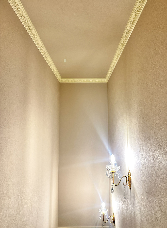 ロココ調モールディングを施した廊下天井と、クラシックなブラケット照明によるエレガントな内装デザイン